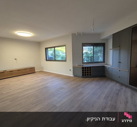 סלון דירה מבריק ונקי לאחר שיפוץ עם רצפת פרקט וחלונות